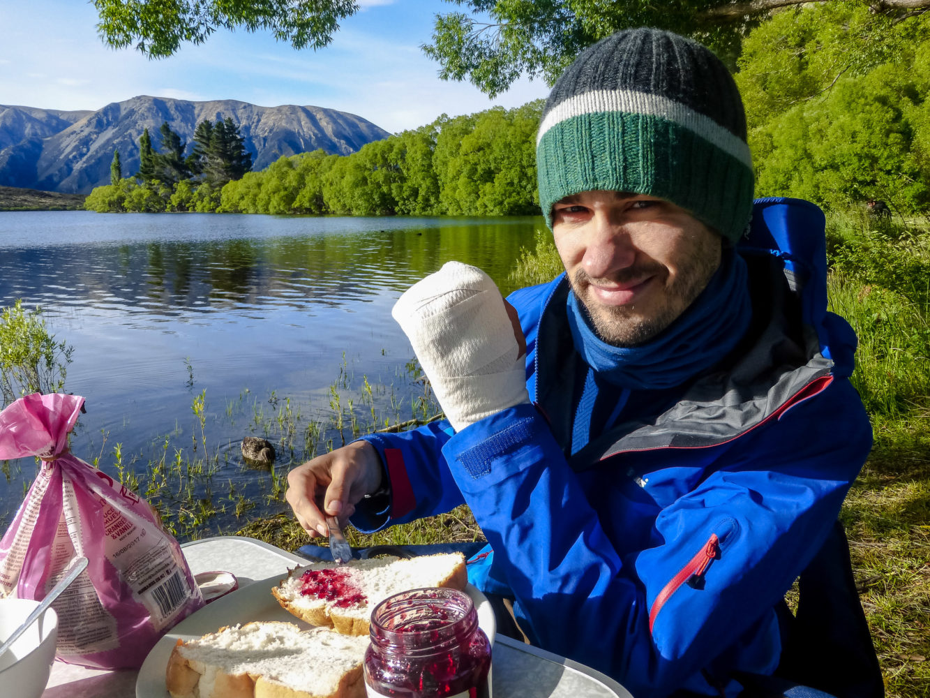 Jan Becker schmiert Marmelade auf ein Toastbroat an einem See