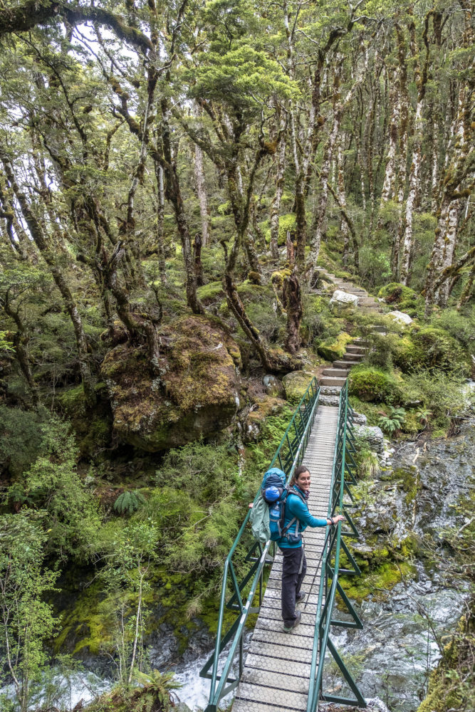 Eine Frau geht über eine Brücke im Wald