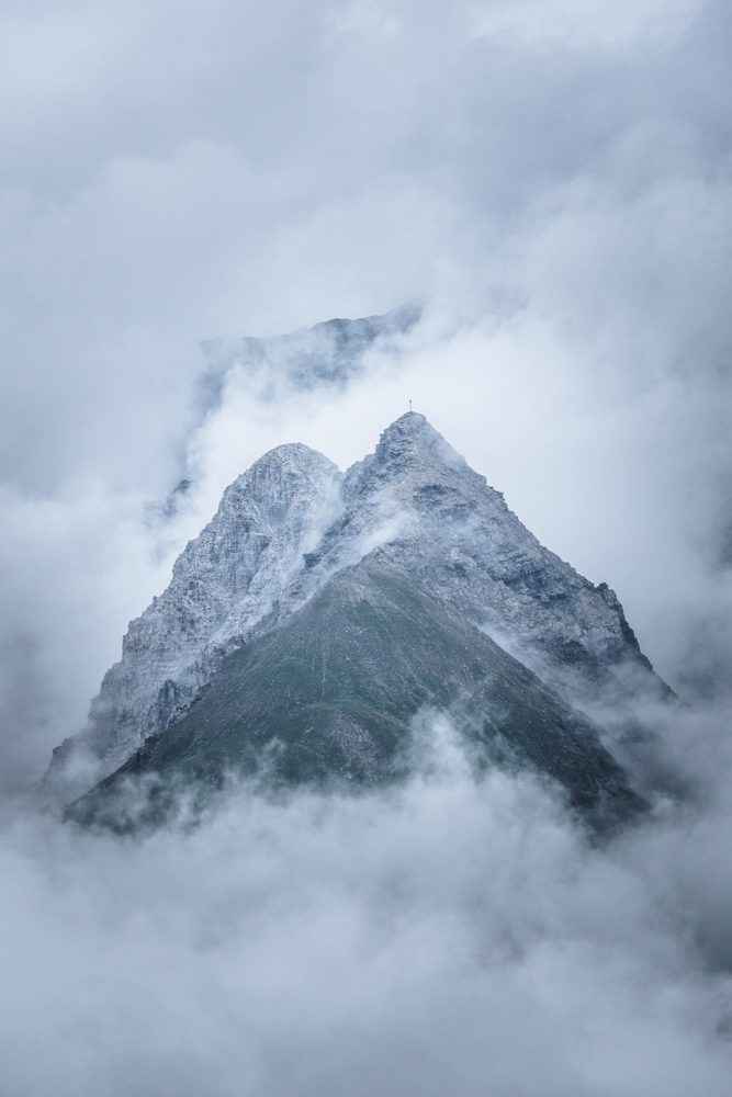 Gipfelspitze zwischen den Wolken in den Alpen bei Bivio