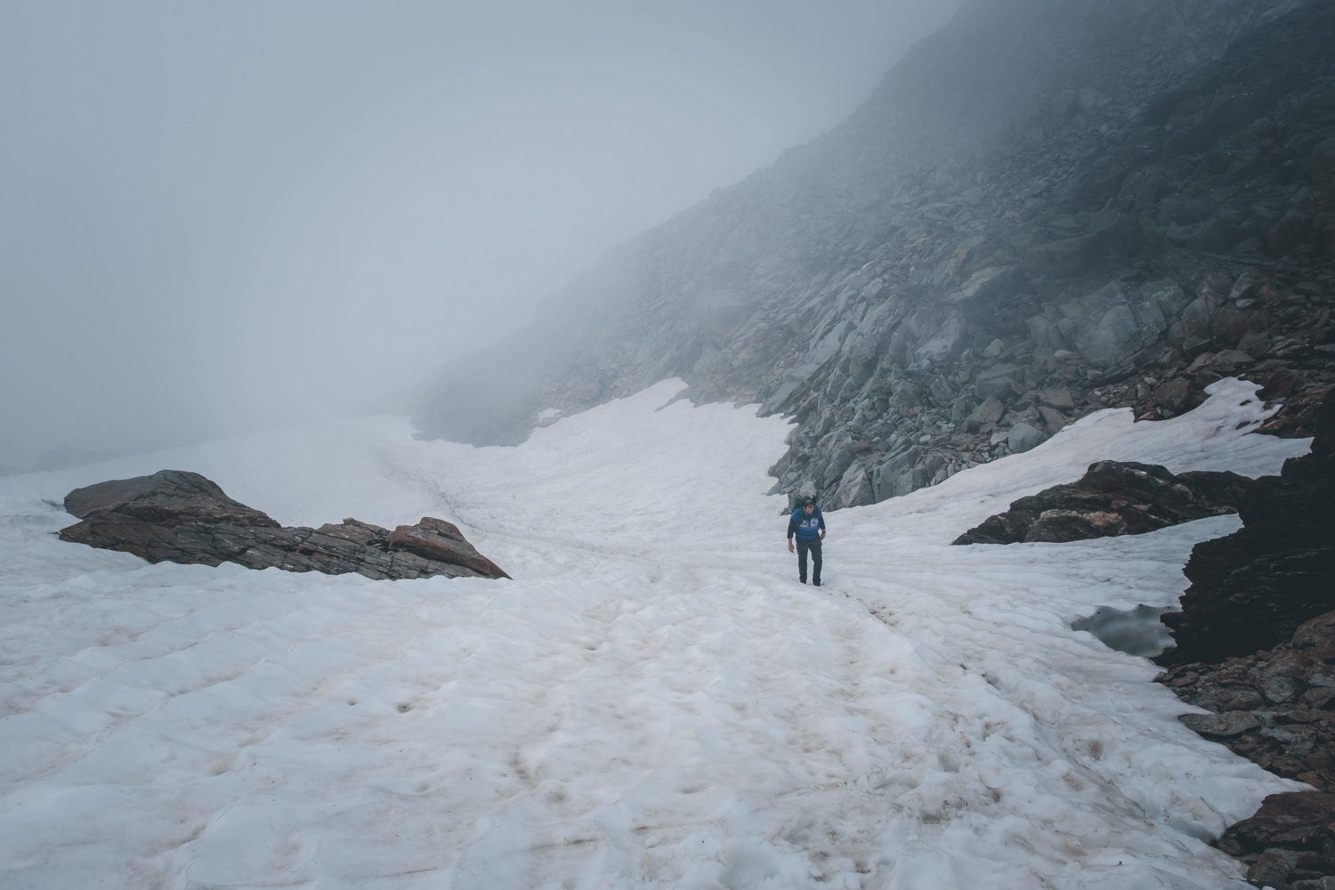 Wanderer geht durch Altschneefeld