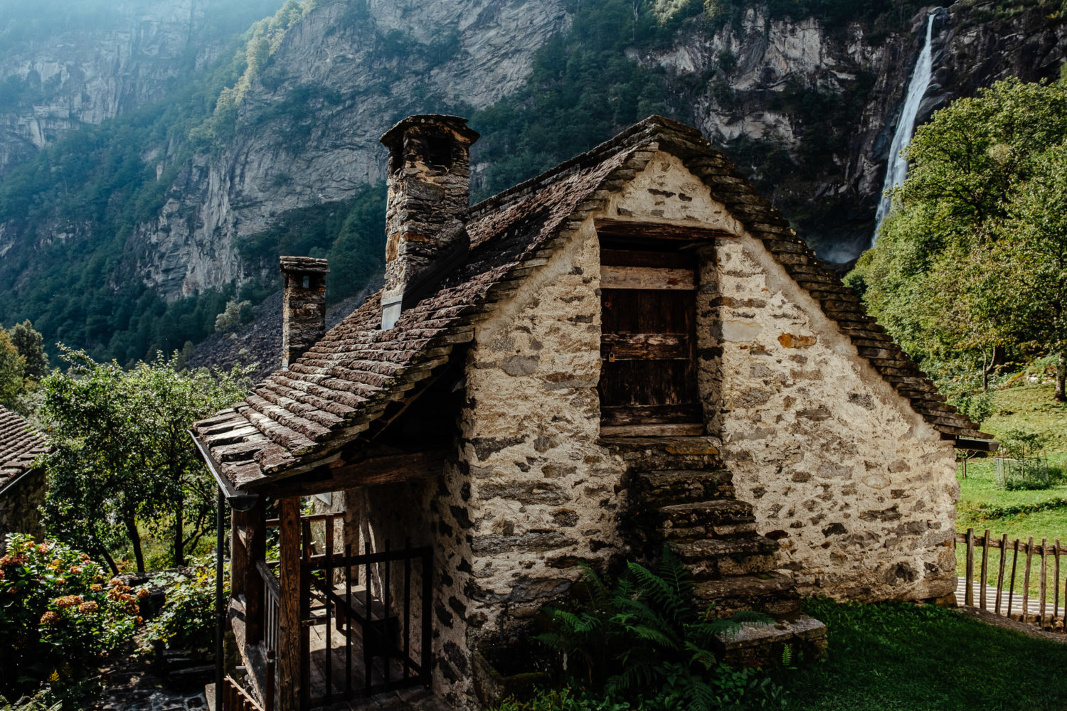 Steinhaus in Foroglio im Val Bavona mit einem Wasserfall im Hintergrund