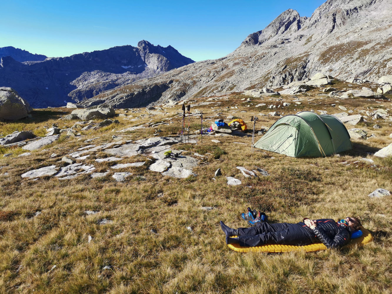 Wanderer liegt auf seiner Isomatte neben seinem Zelt in der Sonne